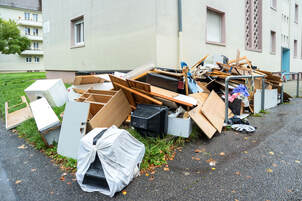 picture of a large pile of trash outside apartment complex including appliances and other items